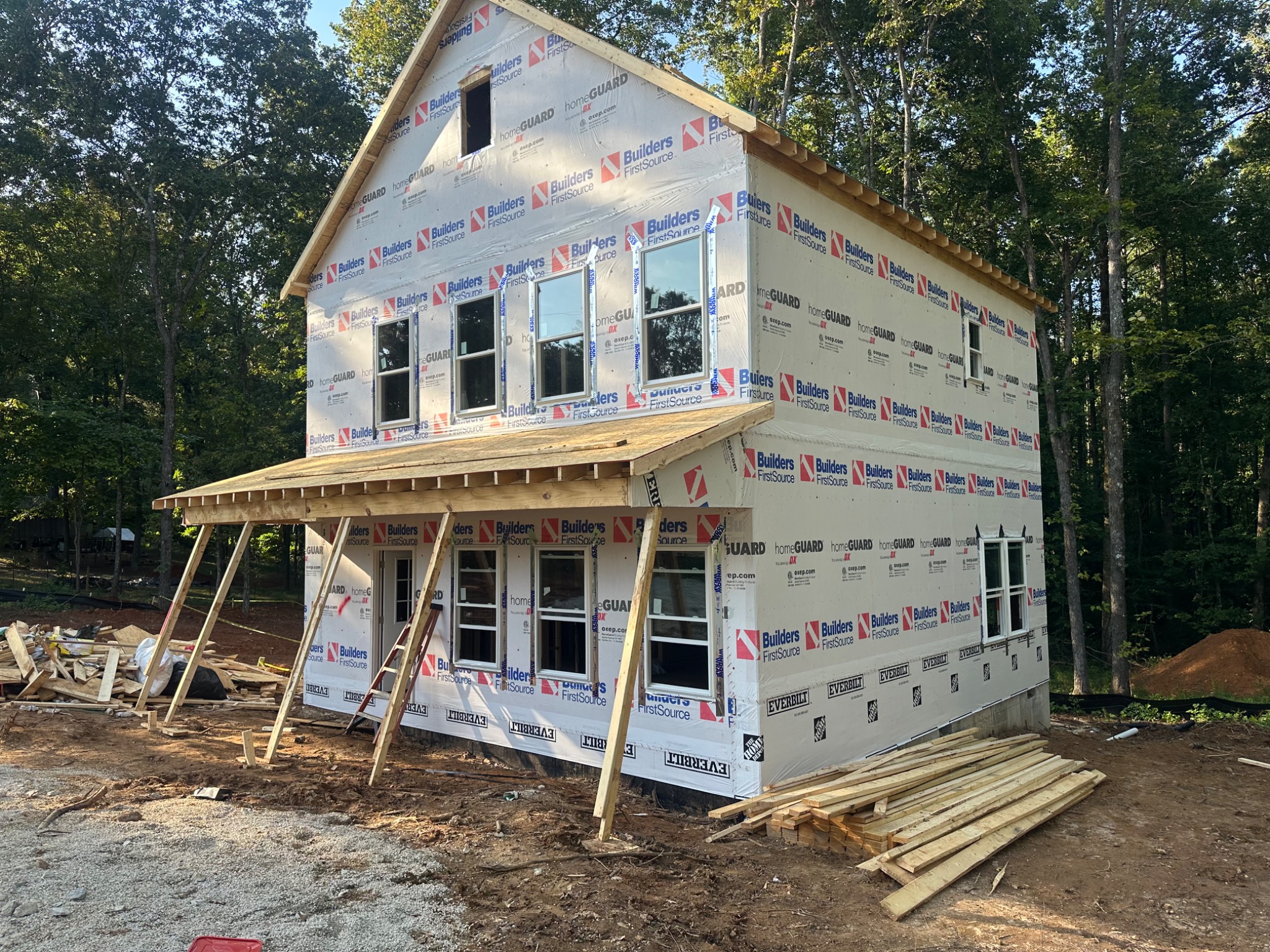 Wrapped house exterior with several installed windows and an entry door